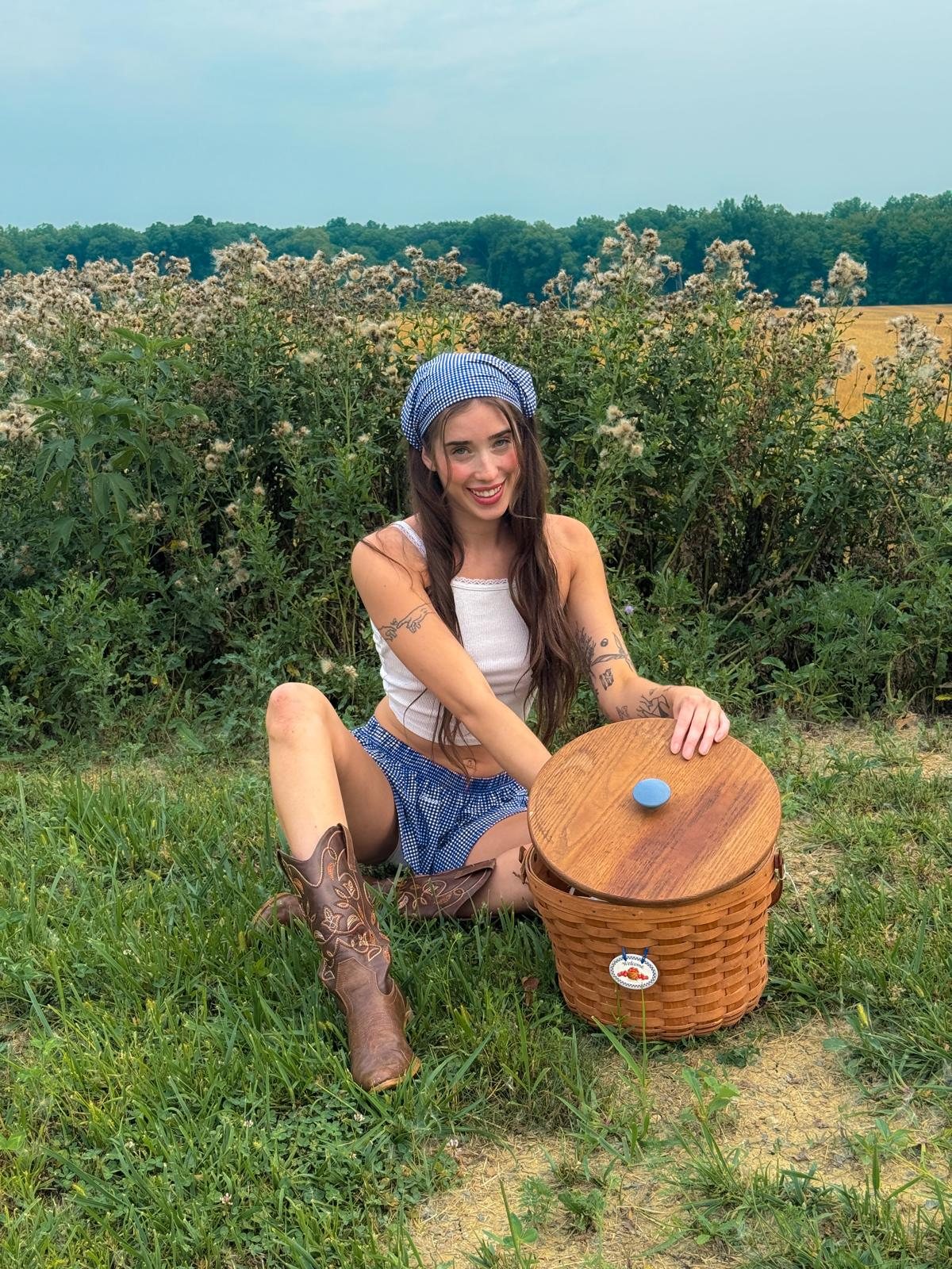 Livinia in a blue gingham headscarf and cowboy boots with a picnic basket